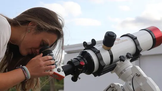 Una chica observa a través de un telescopio. Una chica observa a través de un telescopio.