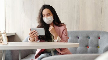Con mascarilla y un smartphone