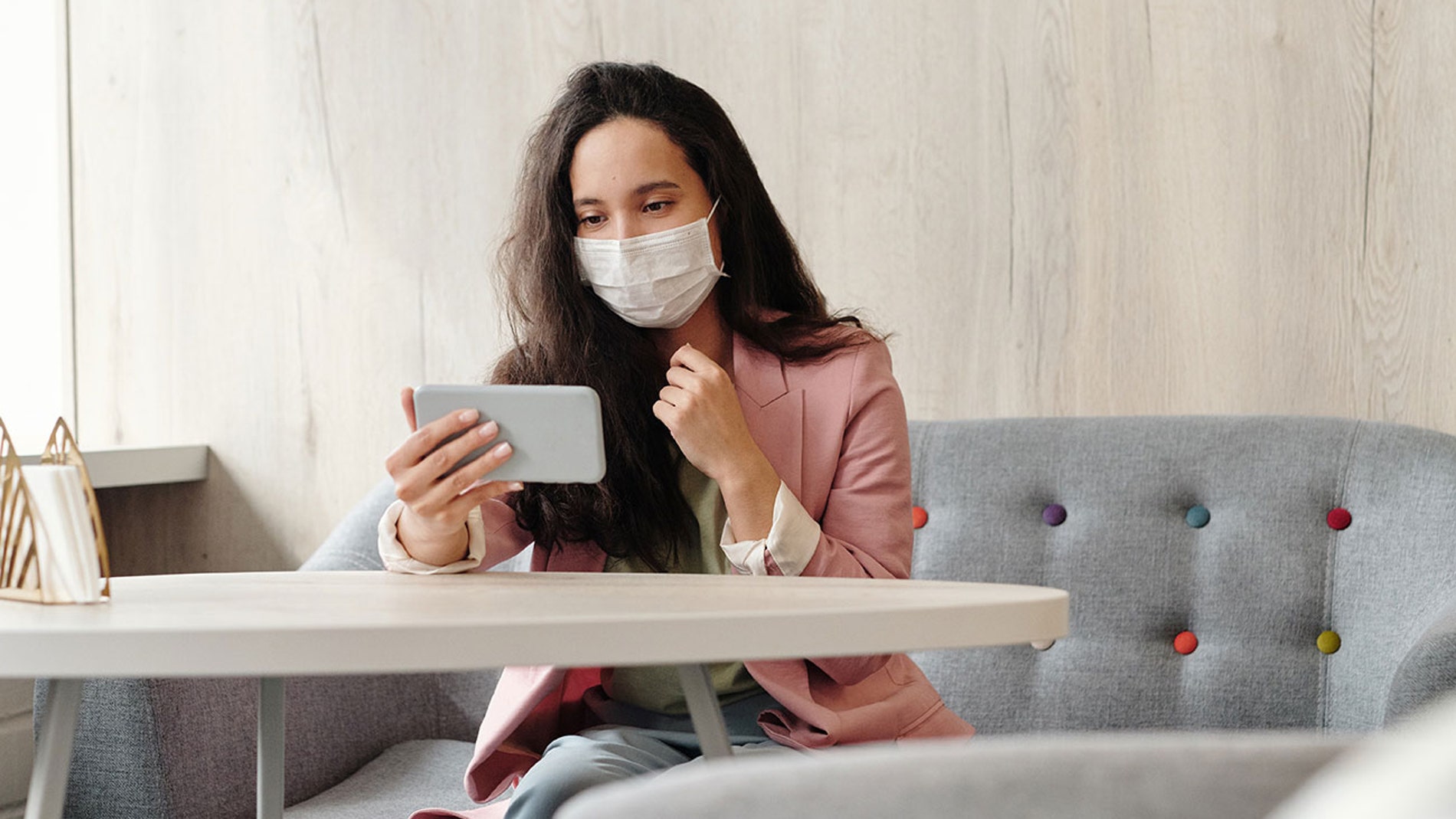 Con mascarilla y un smartphone