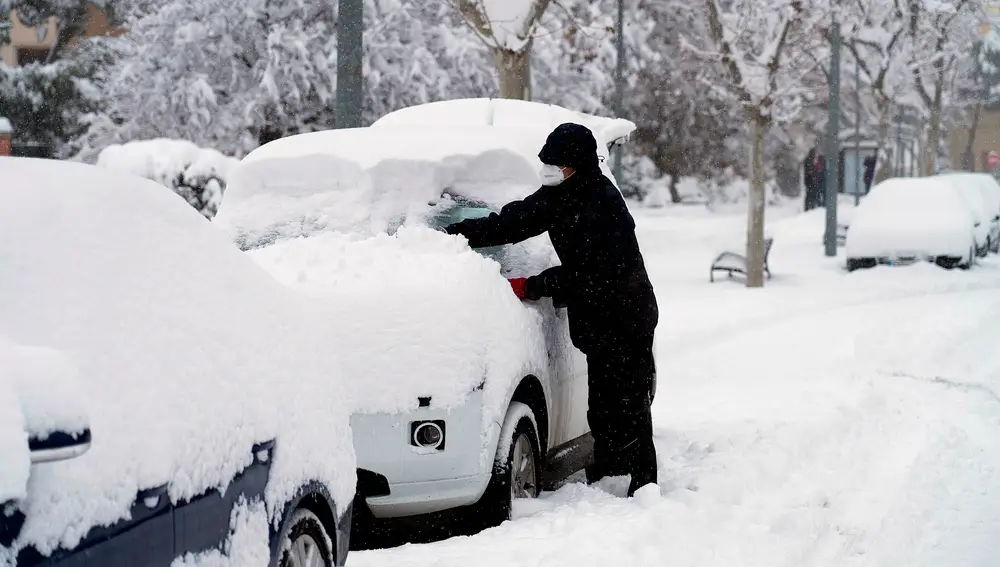 Hombre limpiando nieve de su coche