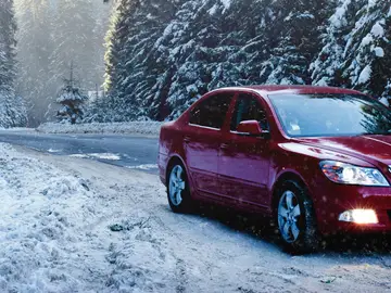 Arrancar el coche con bajas temperaturas Coche rojo circulando por una carretera helada