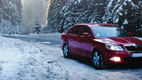 Arrancar el coche con bajas temperaturas Coche rojo circulando por una carretera helada