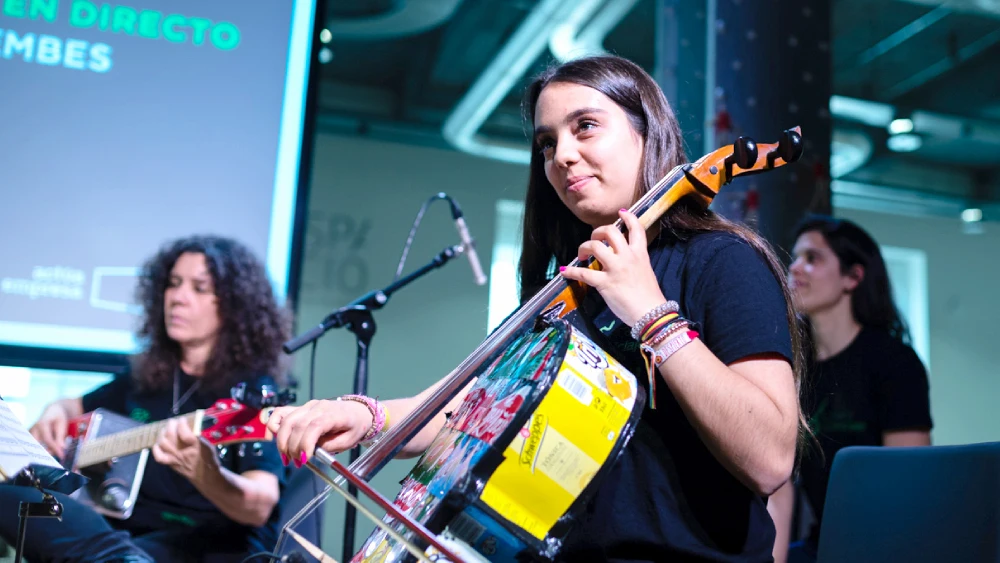 Una joven de la orquesta de 'La música del reciclaje' toca un instrumento construido con residuos