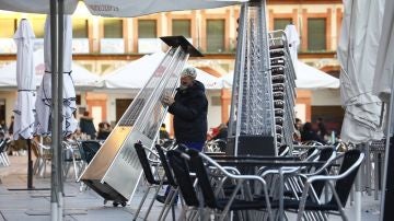 Un trabajador recoge el mobiliario de la terraza de un restaurante en el centro de Córdoba