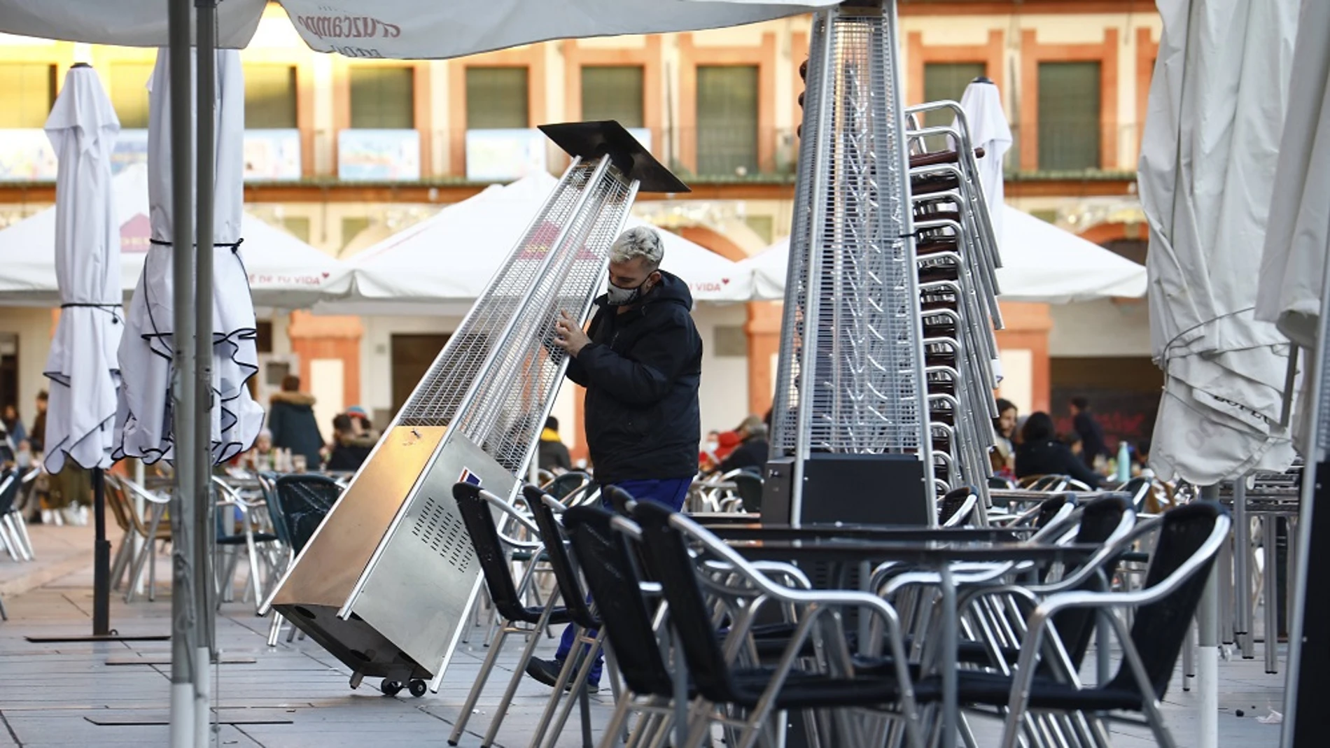 Un trabajador recoge el mobiliario de la terraza de un restaurante en el centro de Córdoba
