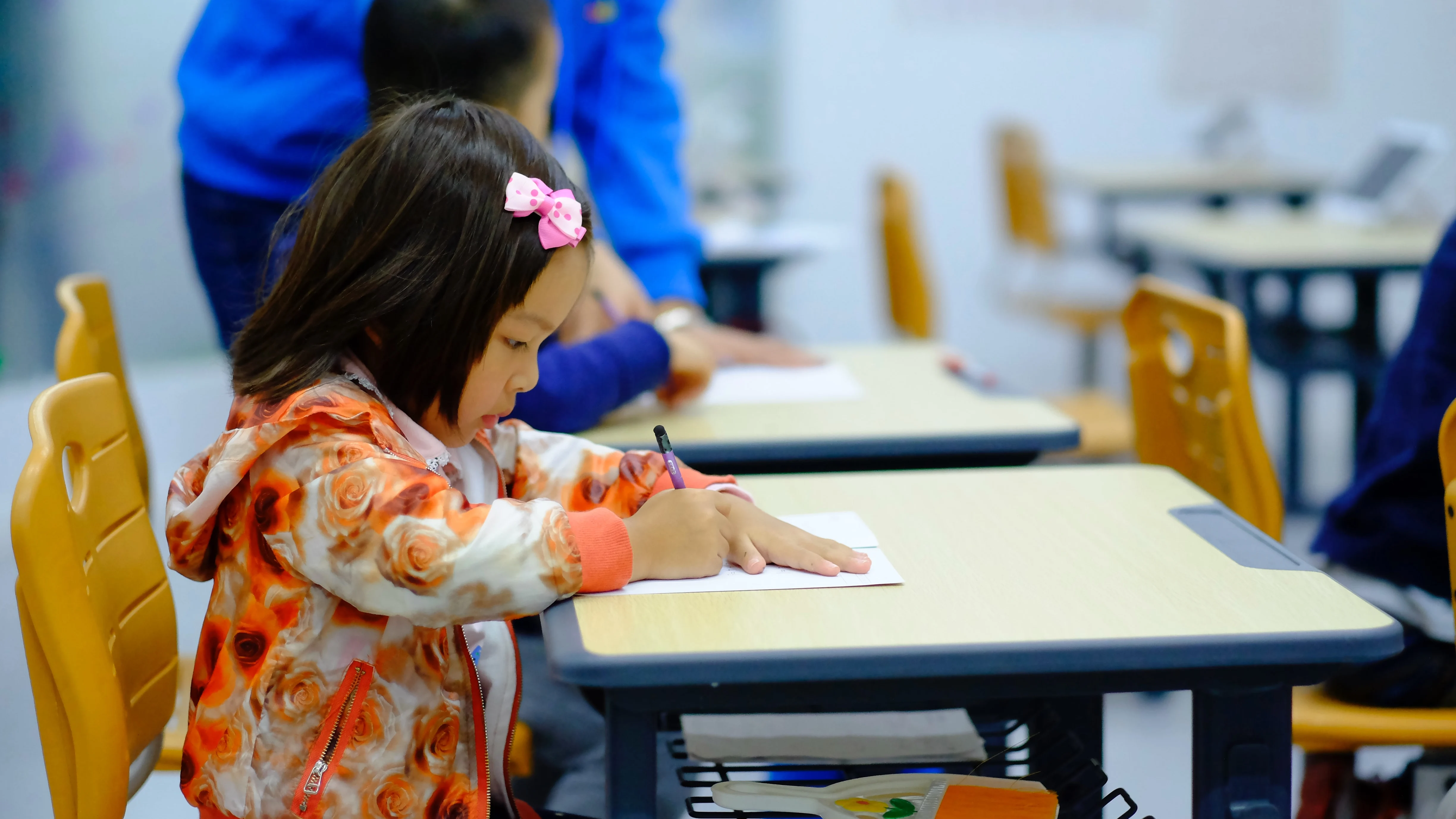 Niña de corta edad pinta sobre en papel en el colegio