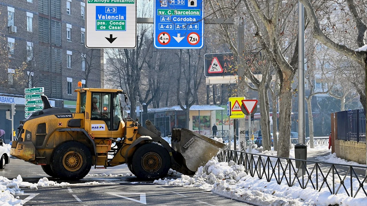 Una excavadora limpia de nieve una calle de Madrid