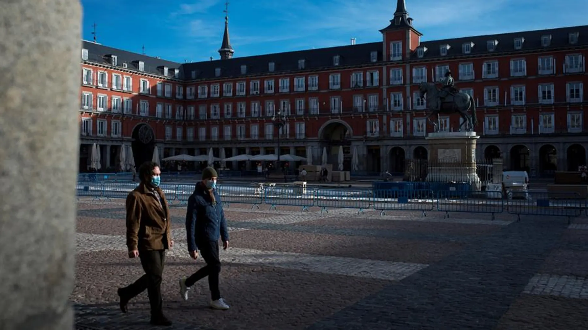 Personas con mascarilla caminan por la Plaza Mayor de Madrid