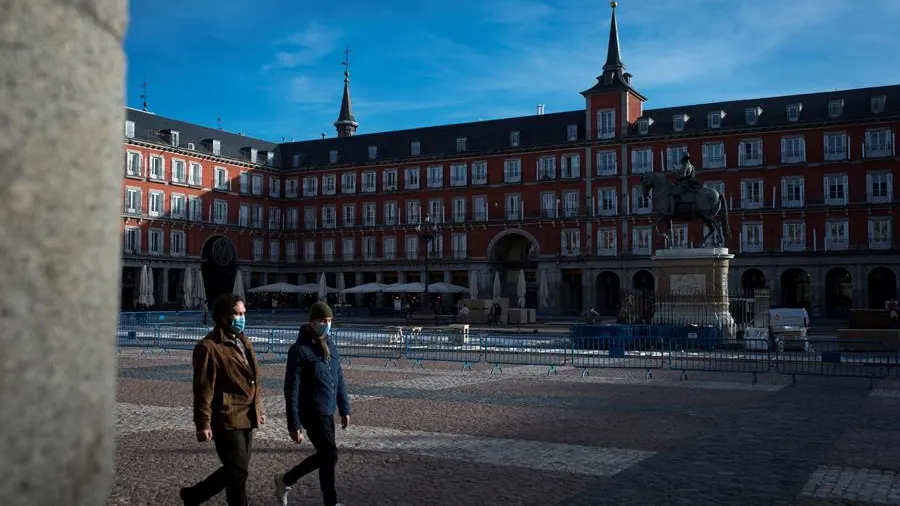 Personas con mascarilla caminan por la Plaza Mayor de Madrid