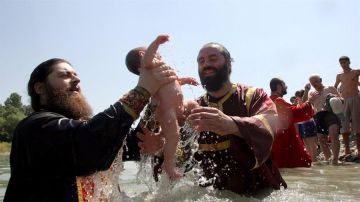 Dos sacerdotes ortodoxos georgianos sostienen un niño durante una ceremonia de Bautismo