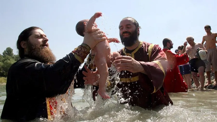 Dos sacerdotes ortodoxos georgianos sostienen un niño durante una ceremonia de Bautismo