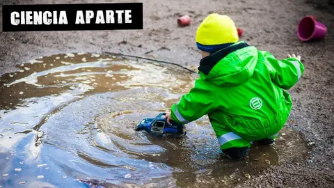 Un niño juega con un coche de juguete en un charco Un niño juega con un coche de juguete en un charco