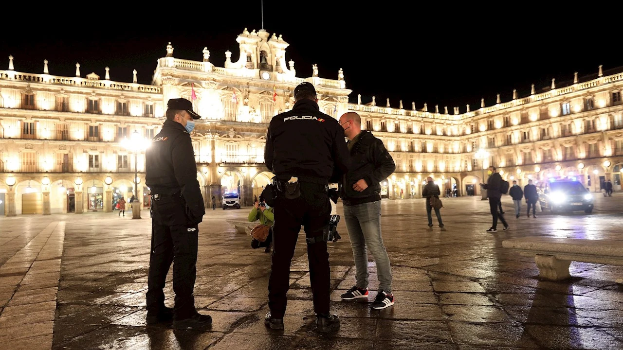 Dos agentes de la Policía Local y Nacional hablan con un ciudadano en la Plaza Mayor de Salamanca (Castilla y León)