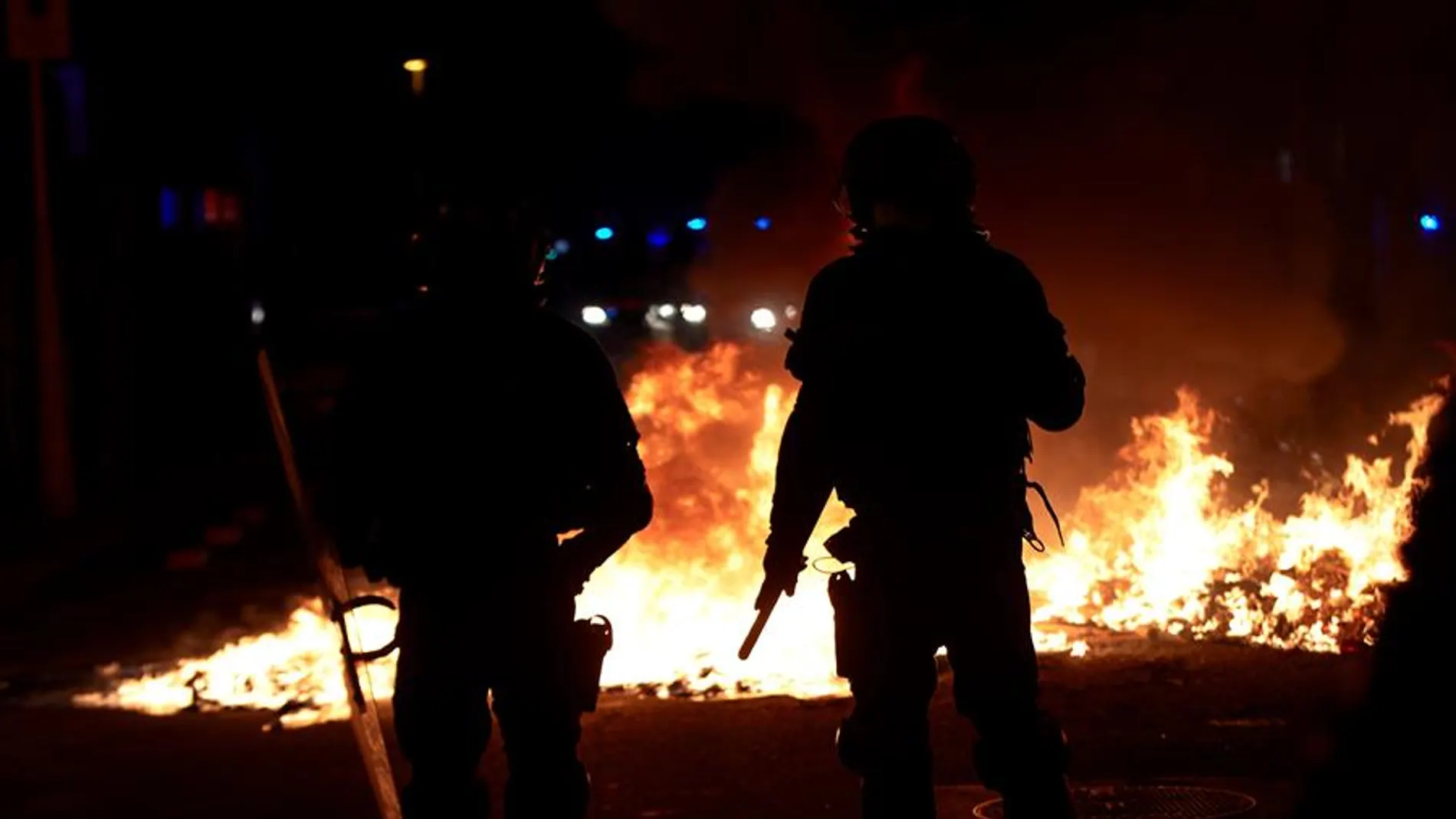 Agentes de los Mossos junto a una barricada en llamas en la Calle Aragó