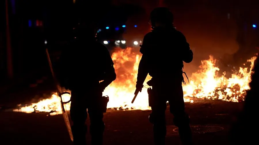 Agentes de los Mossos junto a una barricada en llamas en la Calle Aragó