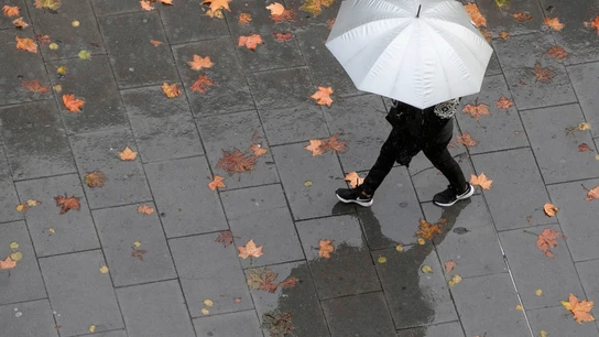 Una persona camina bajo la lluvia Una persona camina bajo la lluvia