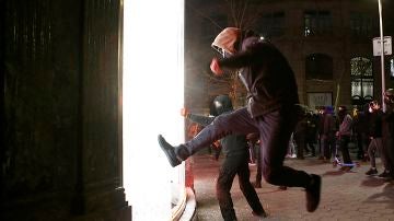 Manifestantes tratan de romper un escaparate de una tienda en el centro de Barcelona
