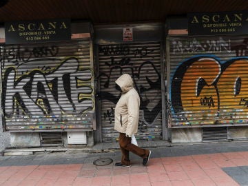 Una persona pasea delante de un local cerrado en Madrid