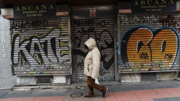 Una persona pasea delante de un local cerrado en Madrid