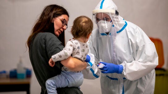 Un sanitario testea a una madre y un hijo en Berl&iacute;n.