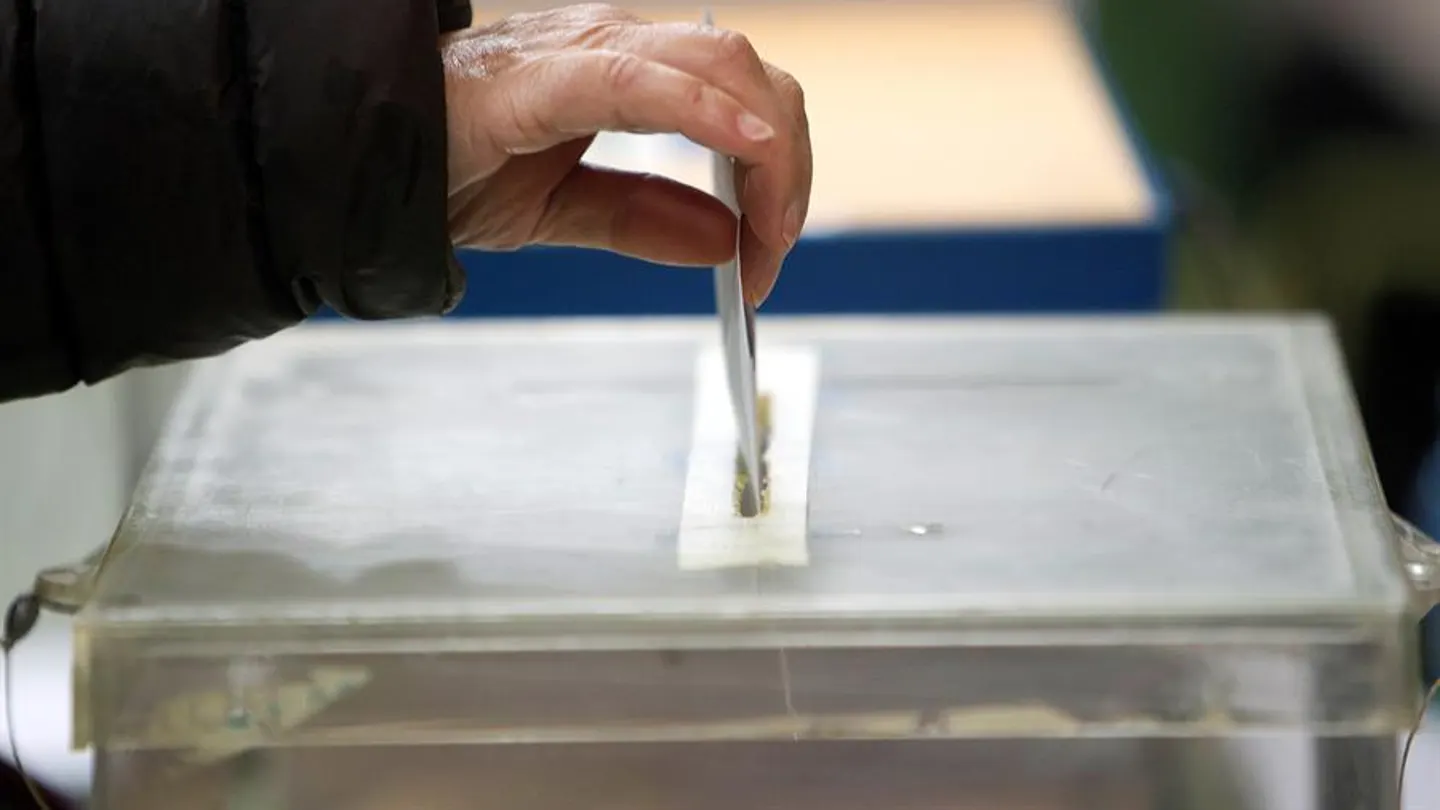 Una persona deposita su voto en una urna Una persona deposita su voto en una urna