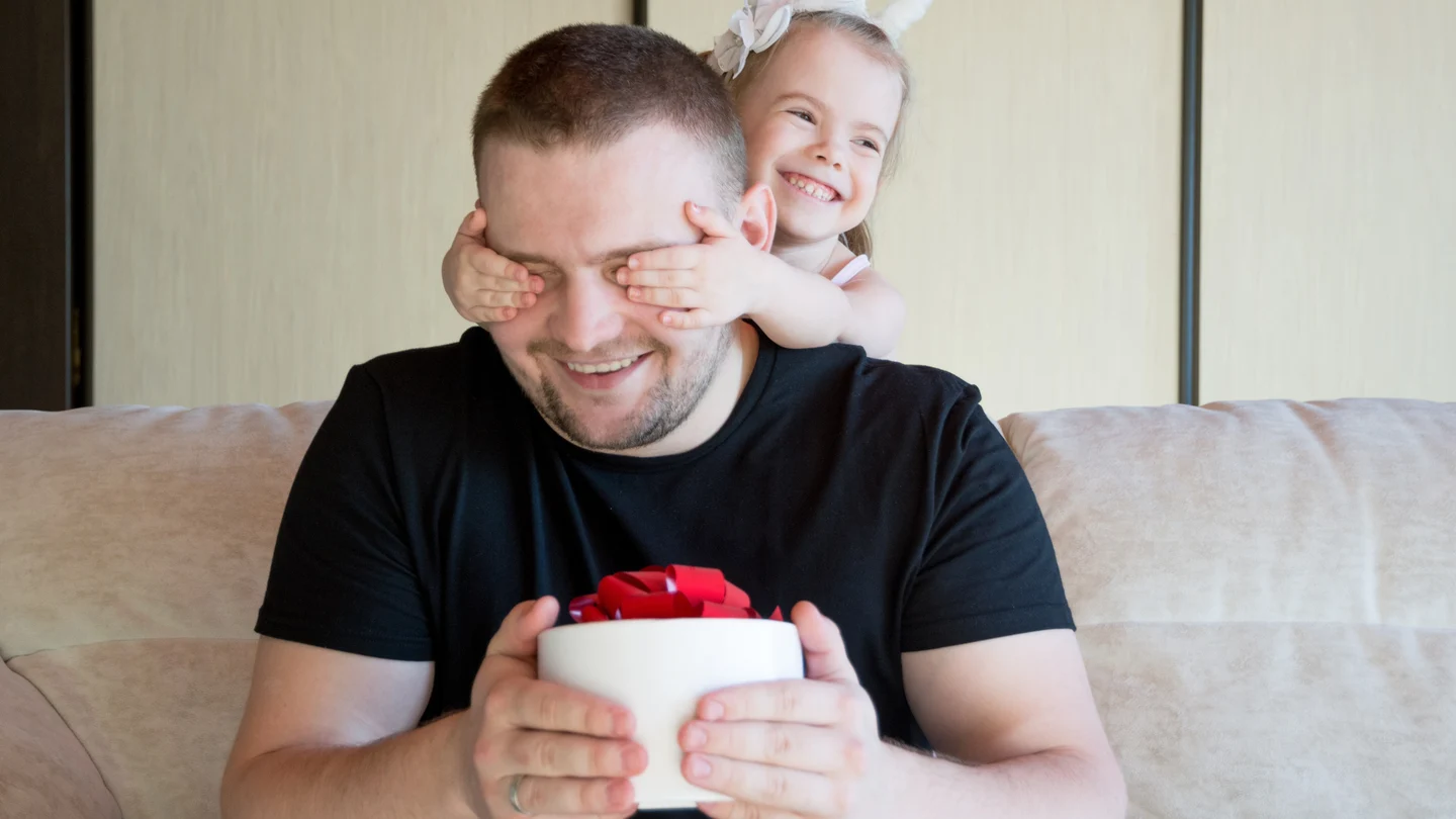¿Cuándo es el Día del Padre 2021? Fechas en España y el resto del mundo Niña pequeña tapa los ojos a su padre al darle un regalo
