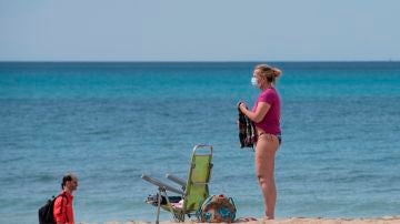 Una mujer utiliza la mascarilla en la playa