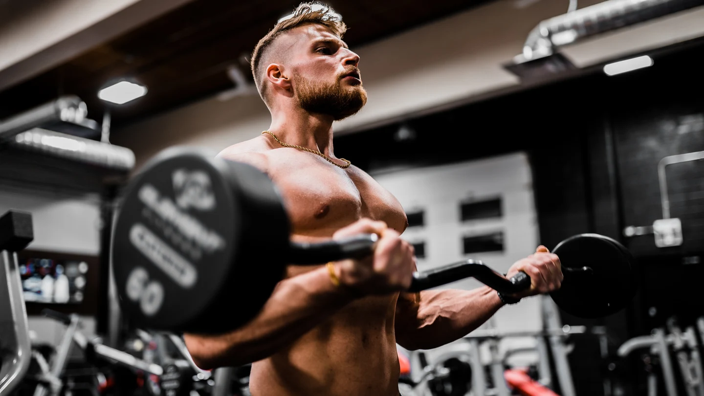 Un hombre entrena en un gimnasio con una barra de pesas Un hombre entrena en un gimnasio con una barra de pesas