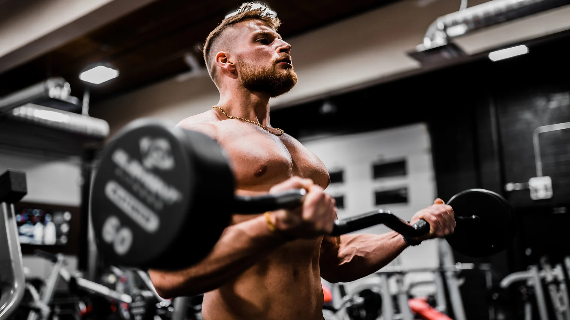 Un hombre entrena en un gimnasio con una barra de pesas