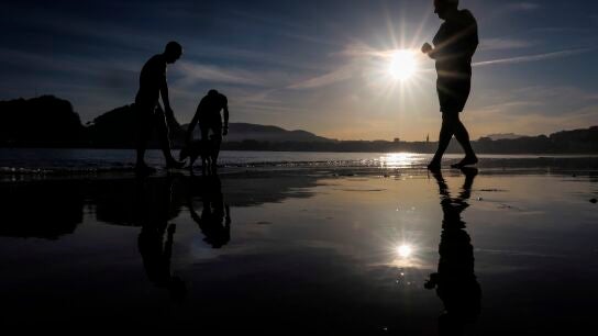 Varias personas se ba&ntilde;an este jueves al amanecer en la playa de Ondarreta de San Sebasti&aacute;n.