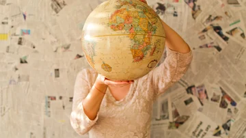 Mujer sostiene una bola del mundo delante de su cabeza