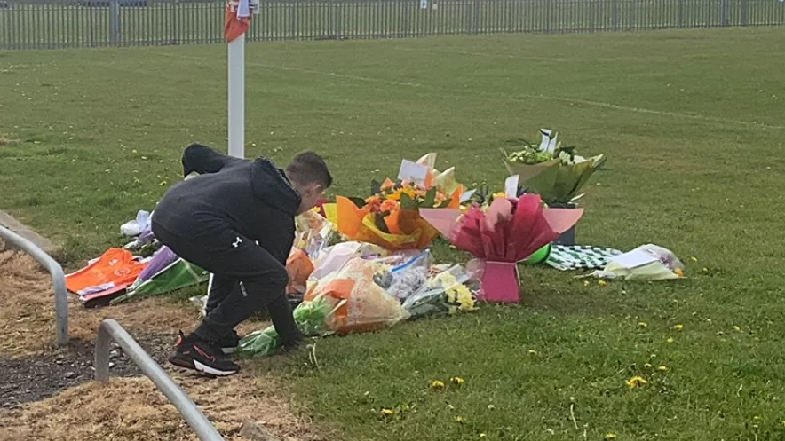 Niño depositando flores en el lugar donde falleció Jordan Banks