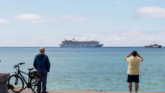 Unos hombres observan un crucero turístico en la bahía de Palma de Mallorca Unos hombres observan un crucero turístico en la bahía de Palma de Mallorca