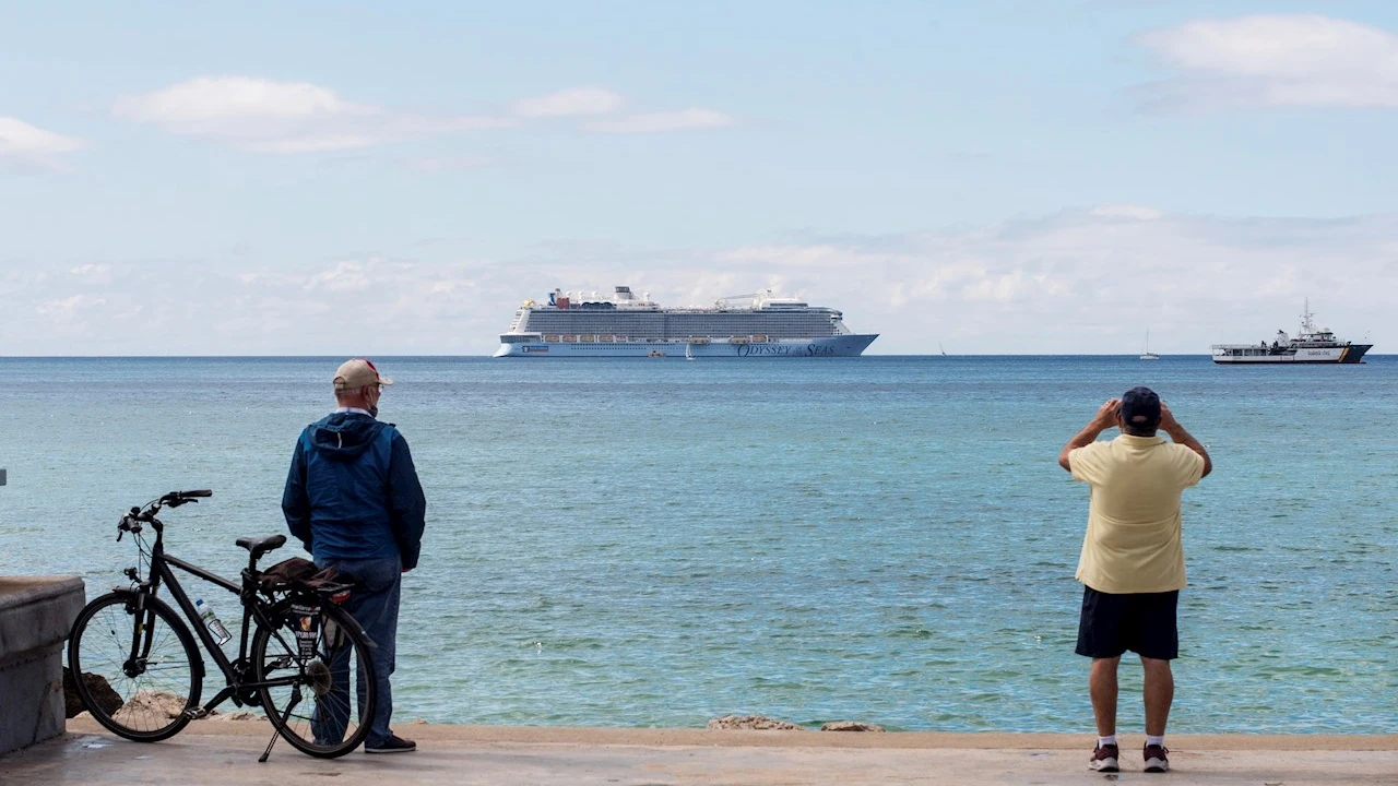 Unos hombres observan un crucero turístico en la bahía de Palma de Mallorca