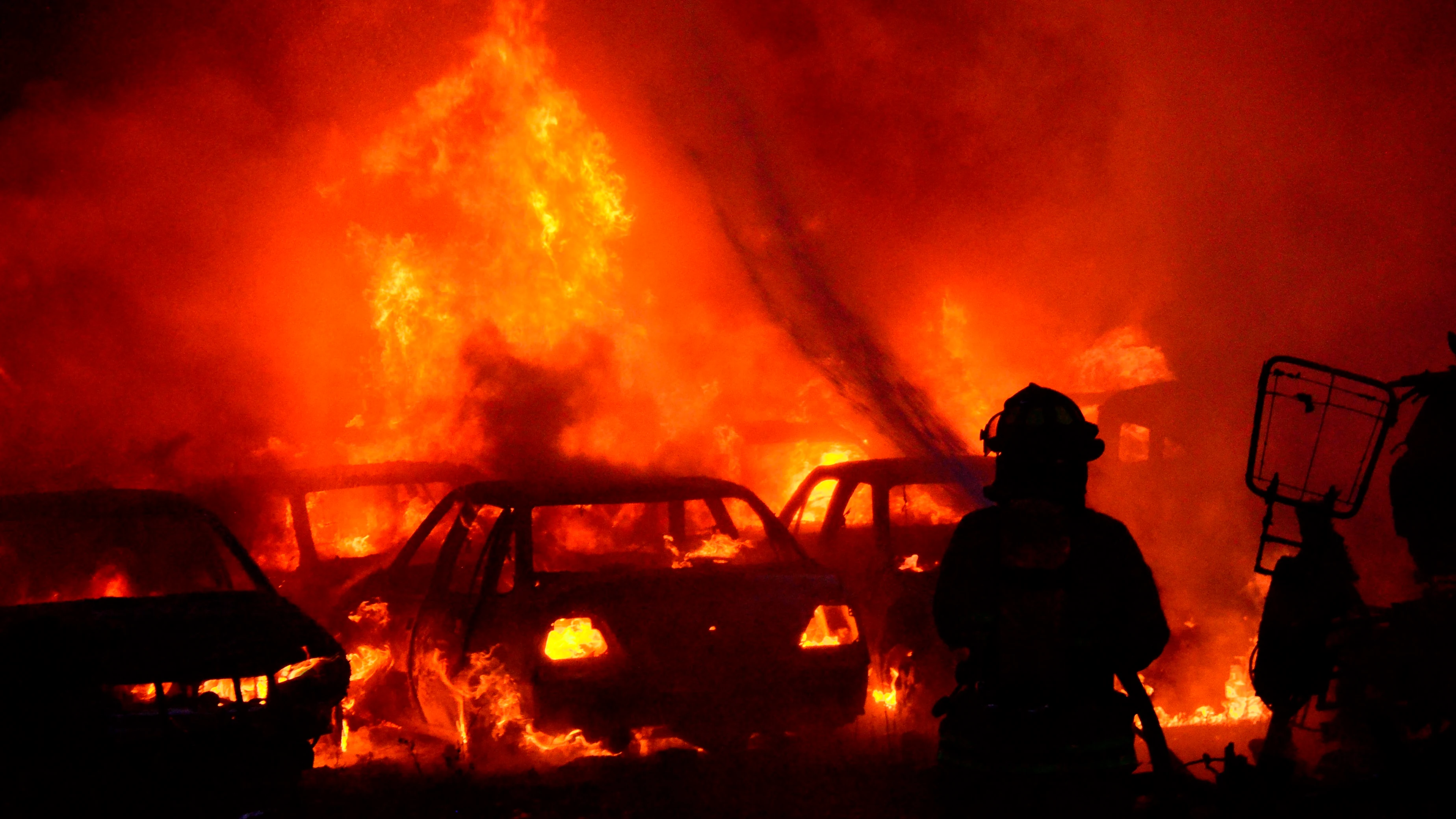 Un bombero intenta apagar un incendio de un estacionamiento del tránsito tras una nueva jornada de protesta en Colombia.