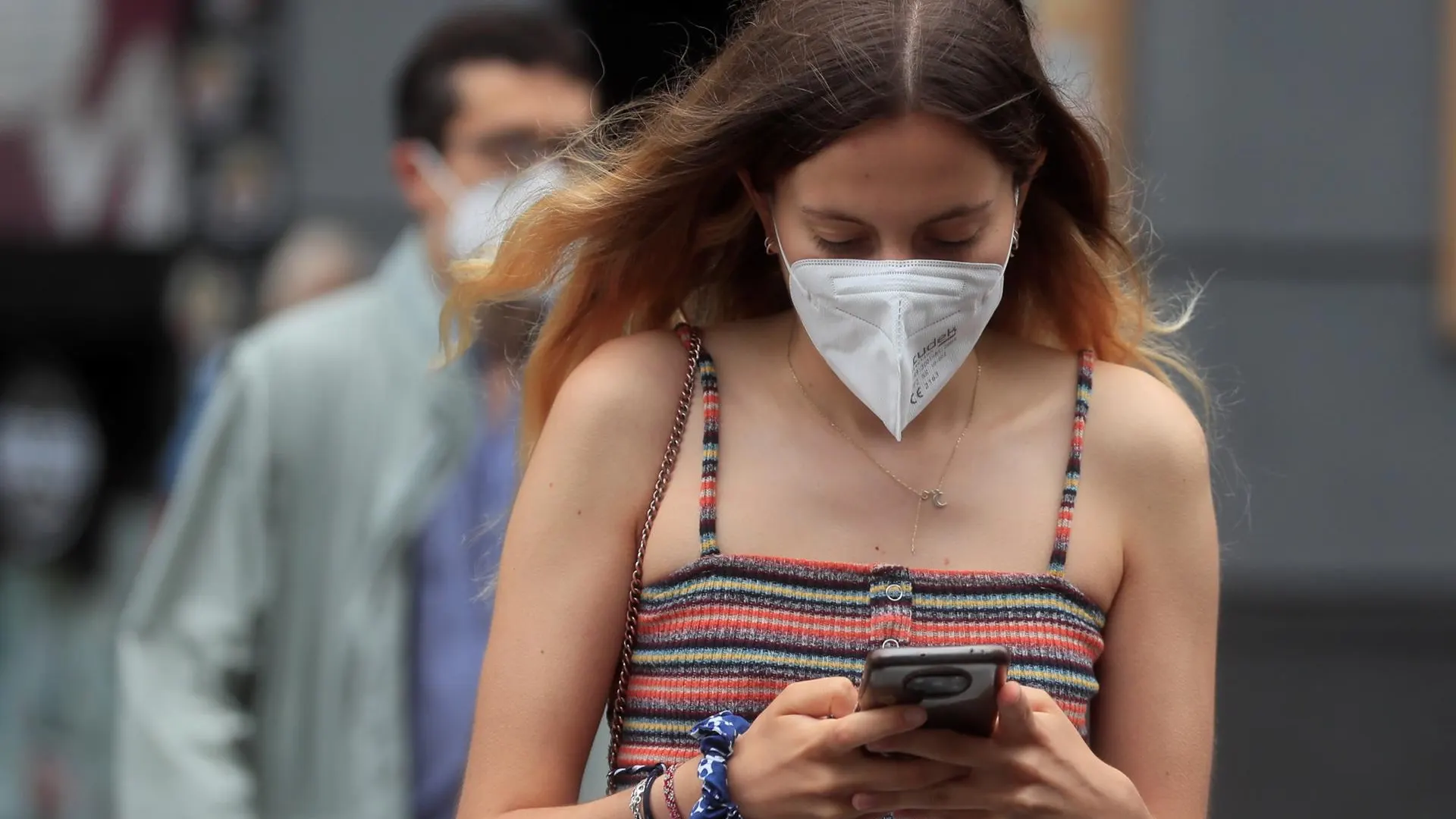 Una joven con mascarilla camina por Madrid