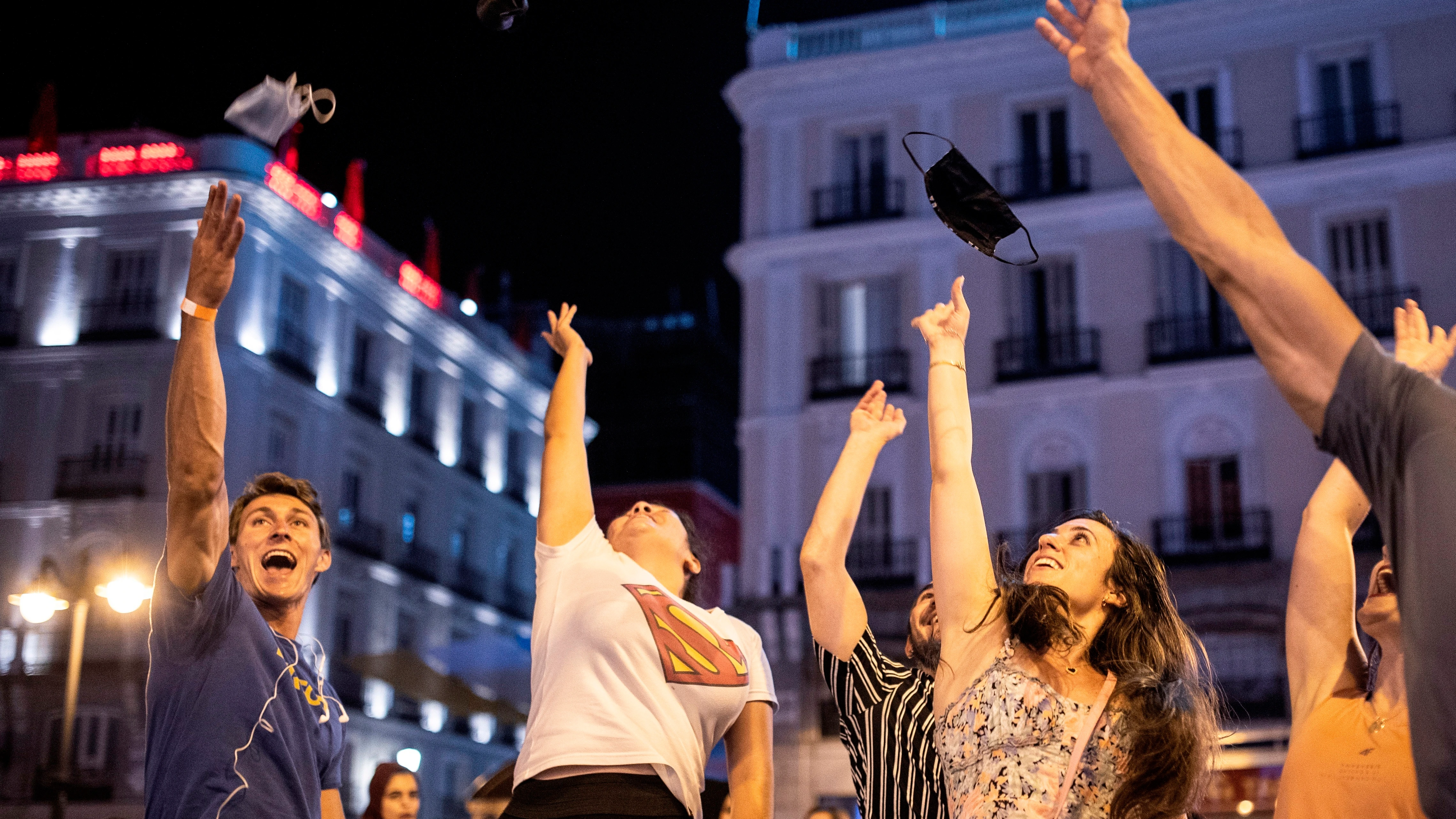 Varios madrileños lanzan las mascarillas al aire después de la entrada en vigor de su exención en el exterior.