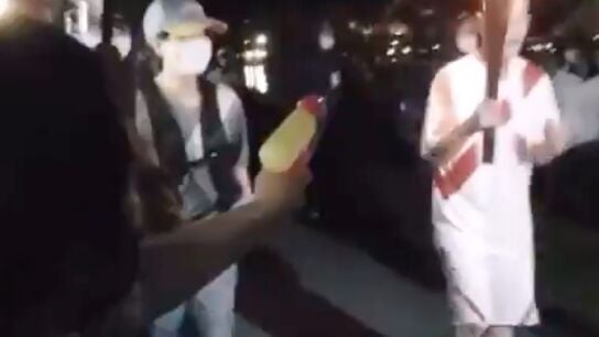 Una mujer dispara con una pistola de agua a la antorcha ol&iacute;mpica 