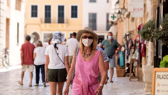 Una mujer caminando con mascarilla por la calle Una mujer caminando con mascarilla por la calle