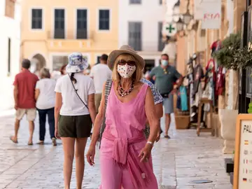 Una mujer caminando con mascarilla por la calle
