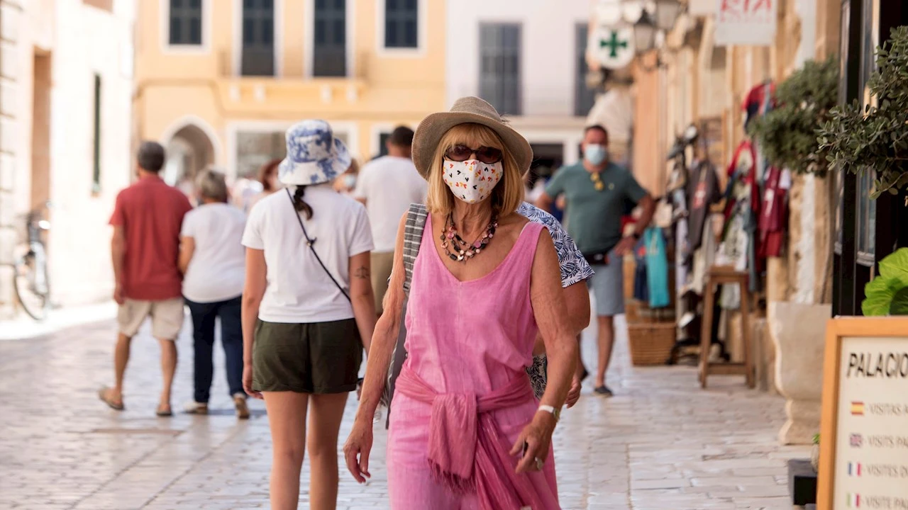 Una mujer caminando con mascarilla por la calle