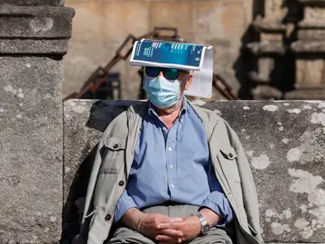 Un hombre se protege del sol con una revista sobre la cabeza en la plaza del Orbadoiro en Santiago de Compostela.