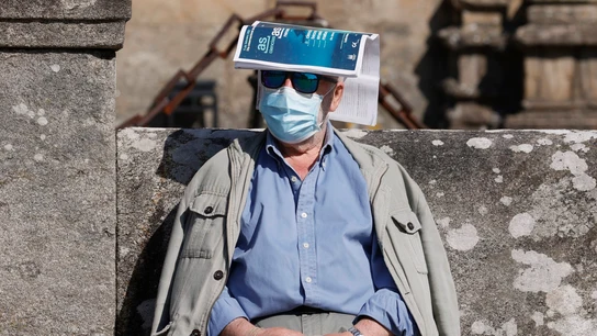 Un hombre se protege del sol con una revista sobre la cabeza en la plaza del Orbadoiro en Santiago de Compostela Un hombre se protege del sol con una revista sobre la cabeza en la plaza del Orbadoiro en Santiago de Compostela