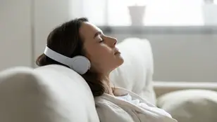 Mujer escucha tranquilamente sus auriculares en el sofá