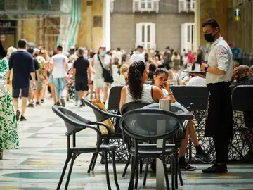 Un camarero atiende a los clientes en la terraza de un restaurante en Nápoles, Italia.