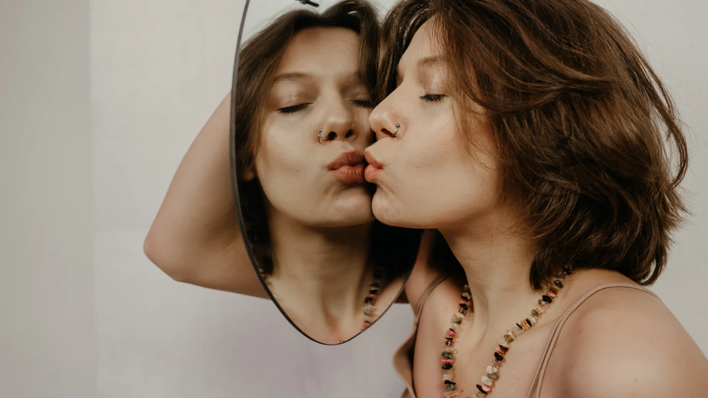 Una mujer mirándose al espejo Una mujer mirándose al espejo