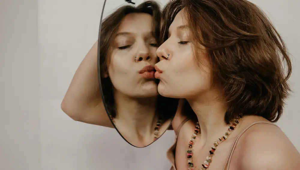 Una mujer mirándose al espejo Una mujer mirándose al espejo