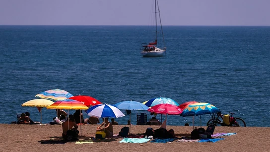 Unos bañistas se protegen del sol bajo las sombrillas en la playa de La Malagueta Unos bañistas se protegen del sol bajo las sombrillas en la playa de La Malagueta