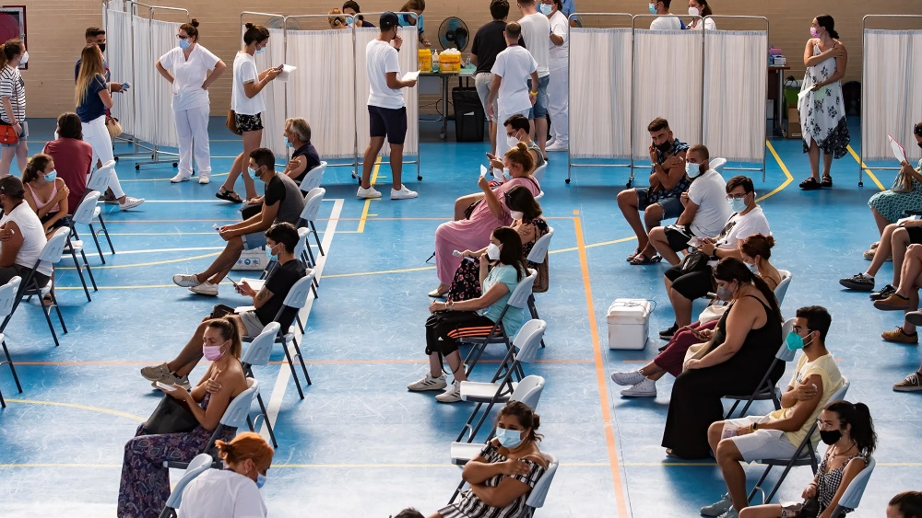 Multitud de jóvenes aguardan sentados tras recibir la vacuna contra el coronavirus