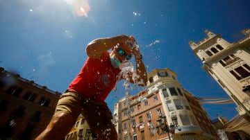 Un hombre se refresca en una fuente en Córdoba.